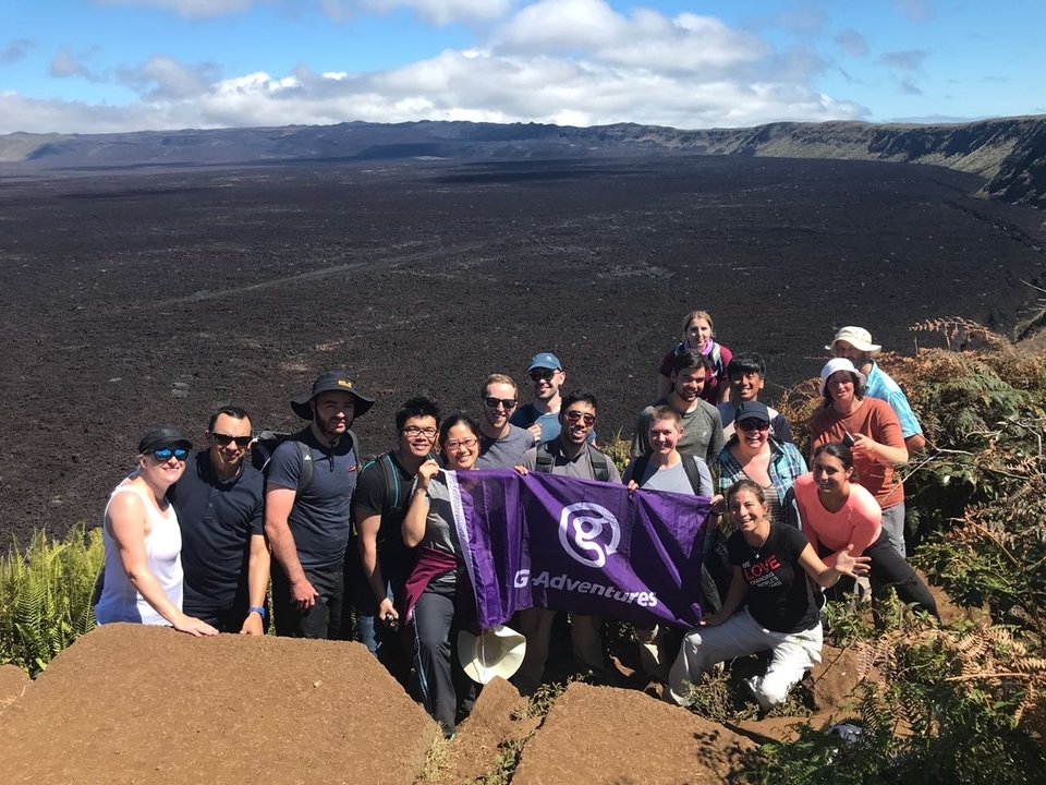 Group of people on a volcanic landscape holding a flag.