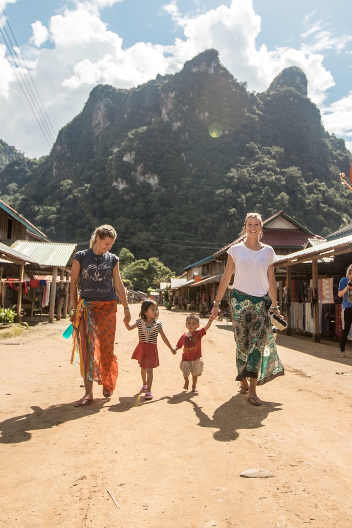 Two women walking with children in a village.