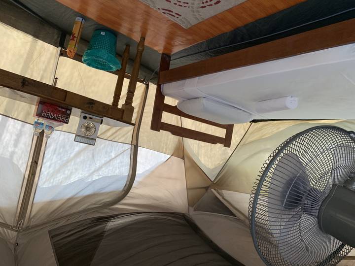 Intérieur de tente de camping avec un lit et une petite table.