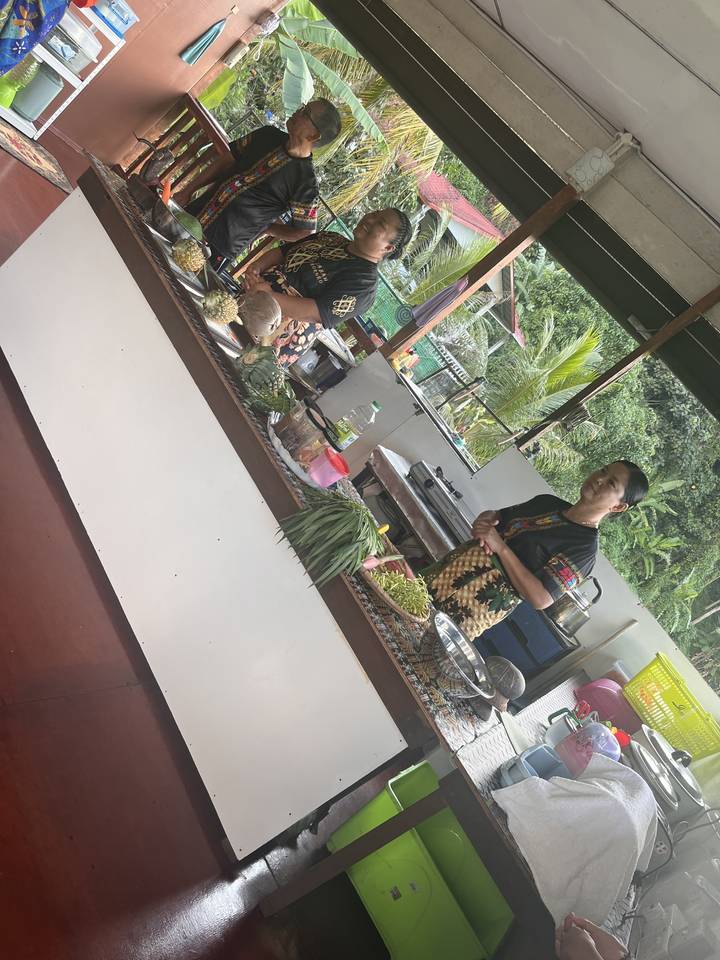 Groupe de personnes préparant de la nourriture traditionnelle dans une cuisine semi-ouverte.