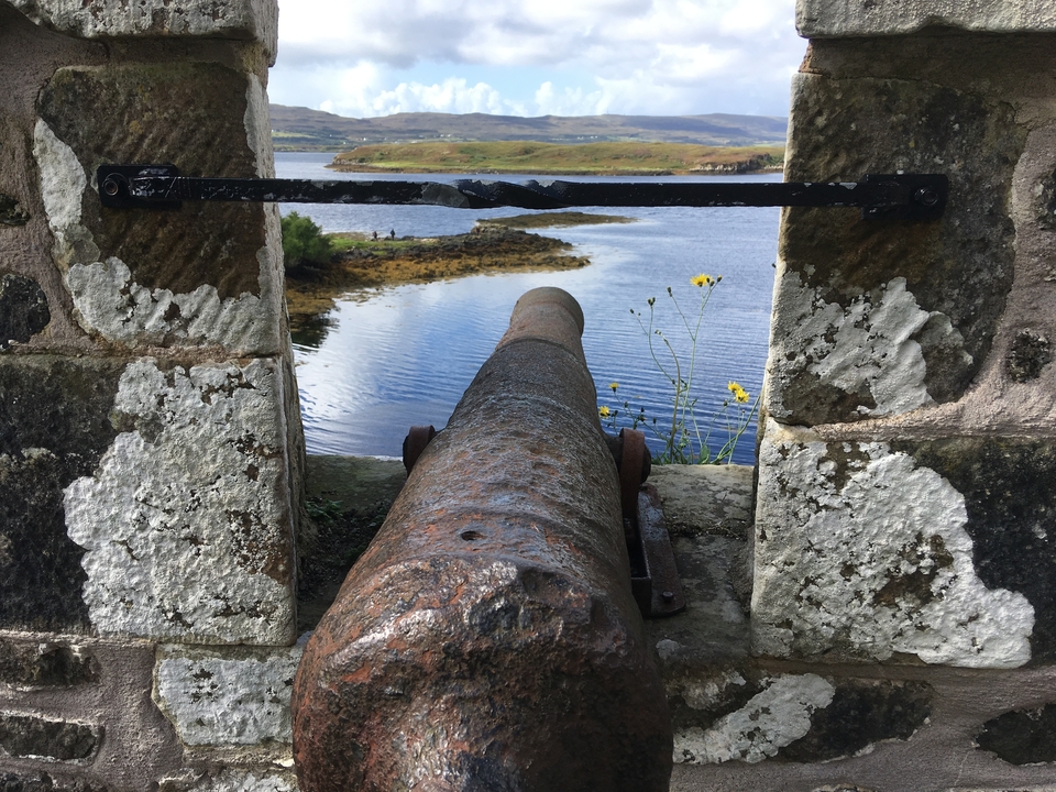 Un canon historique surplombant un lac avec des collines en arrière-plan.
