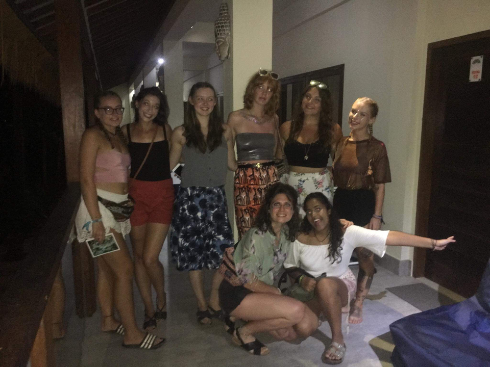 A group of women posing on a balcony at night.