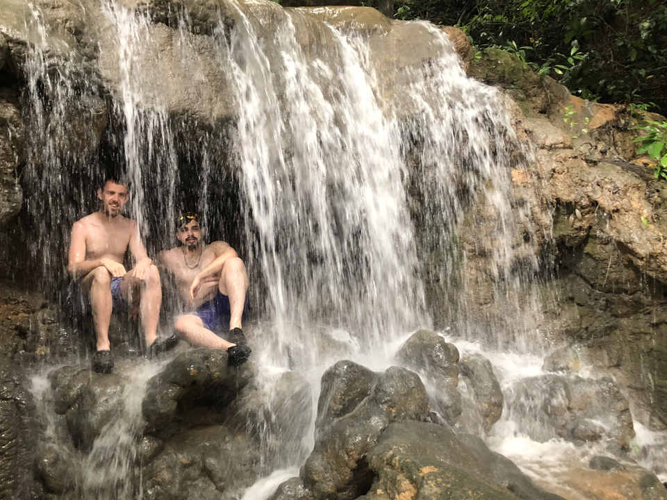 Two people sitting under a waterfall.
