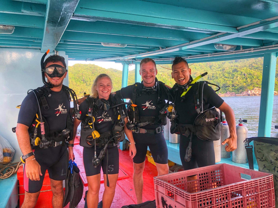 Group of people on a boat wearing scuba gear.