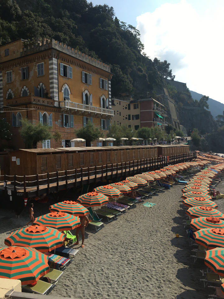 Colorful beach umbrellas along a beach with town buildings.