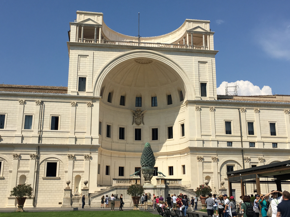 White and ornate building facade with a fountain.
