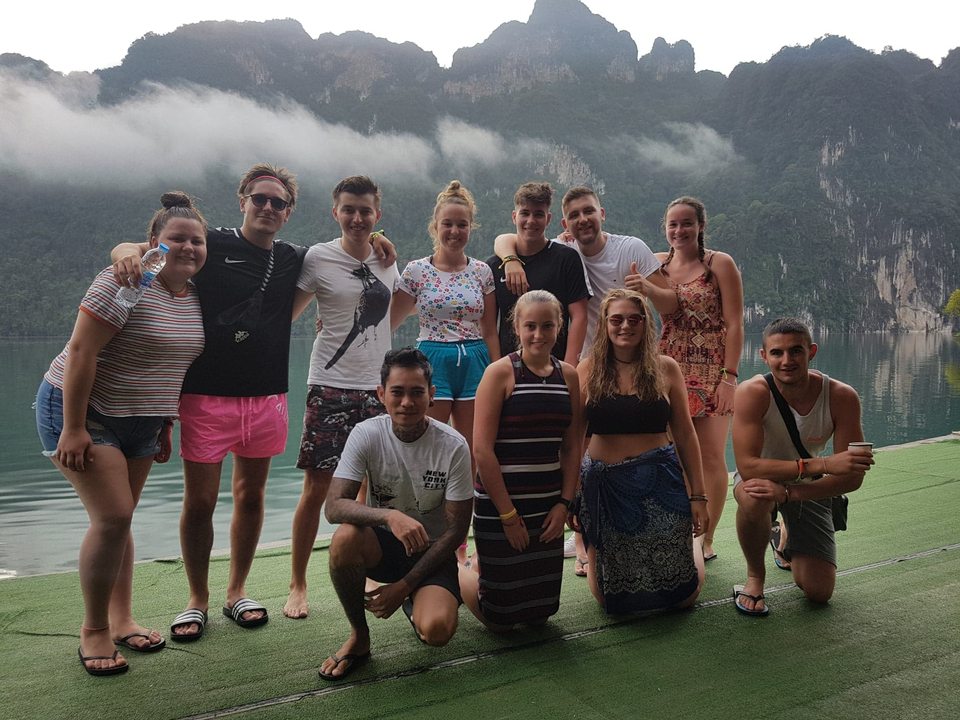 Group of people posing in front of a scenic lake view.