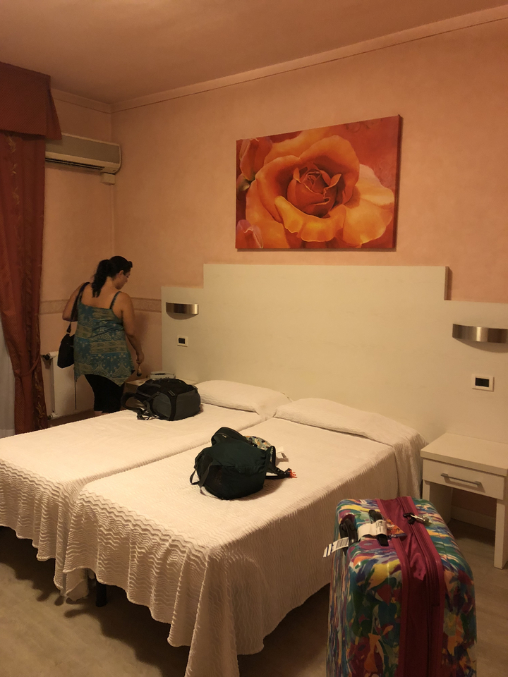 Chambre d'hôtel avec deux lits, une personne et quelques bagages.