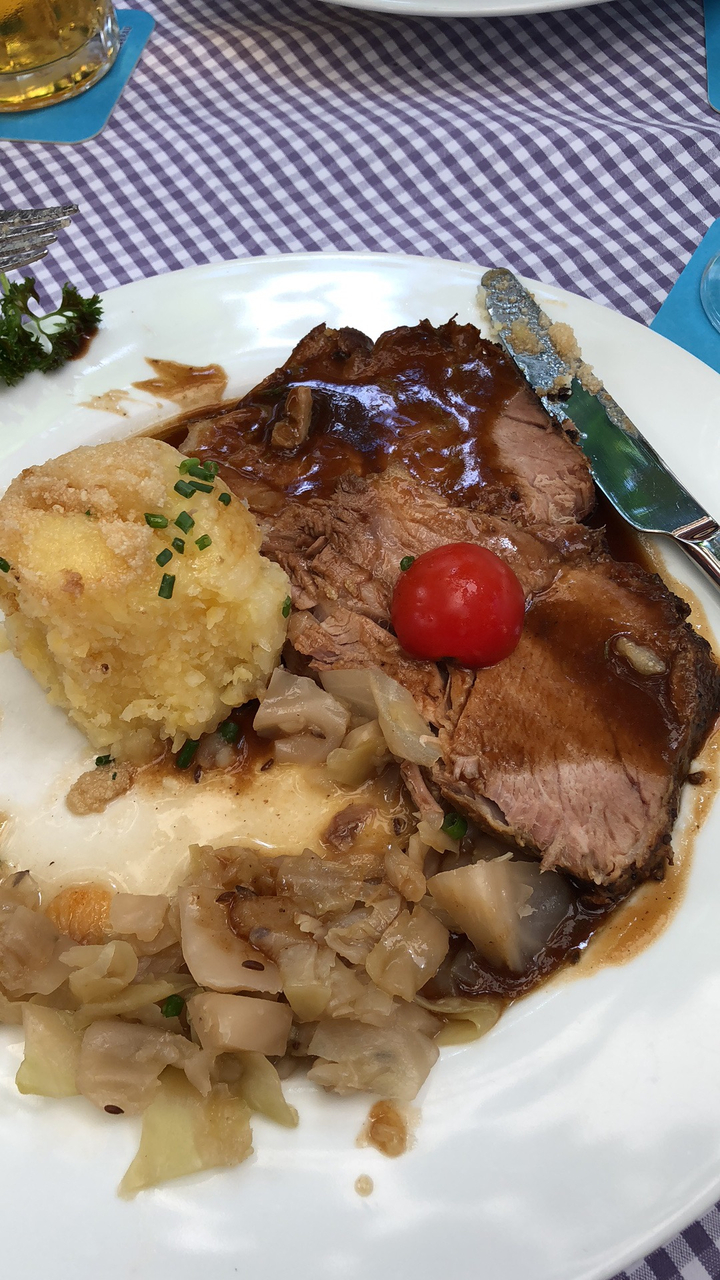 Assiette de rôti tranché avec sauce et une petite tomate cerise.
