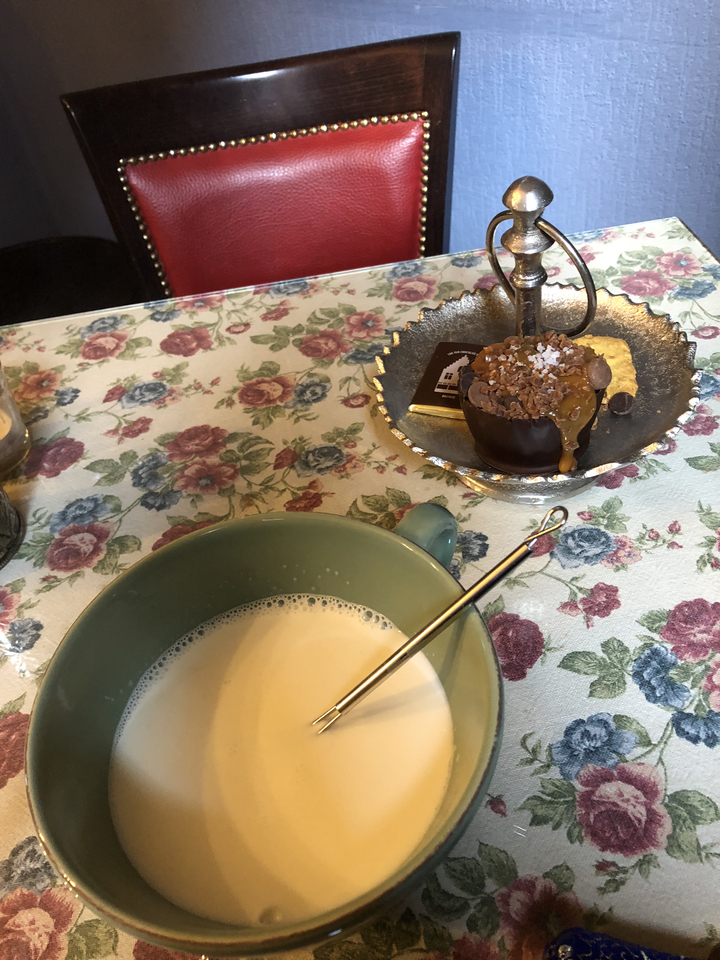 Gros plan d'un dessert et d'une boisson chaude sur une nappe fleurie.