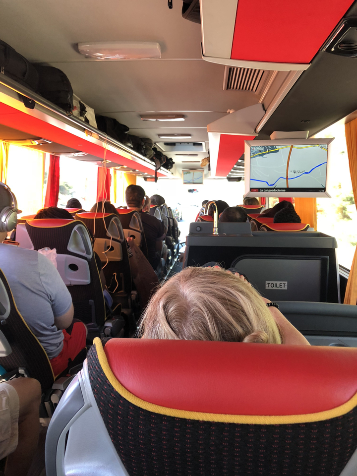 Intérieur d'un autocar de tourisme montrant les passagers et un écran avec une carte.