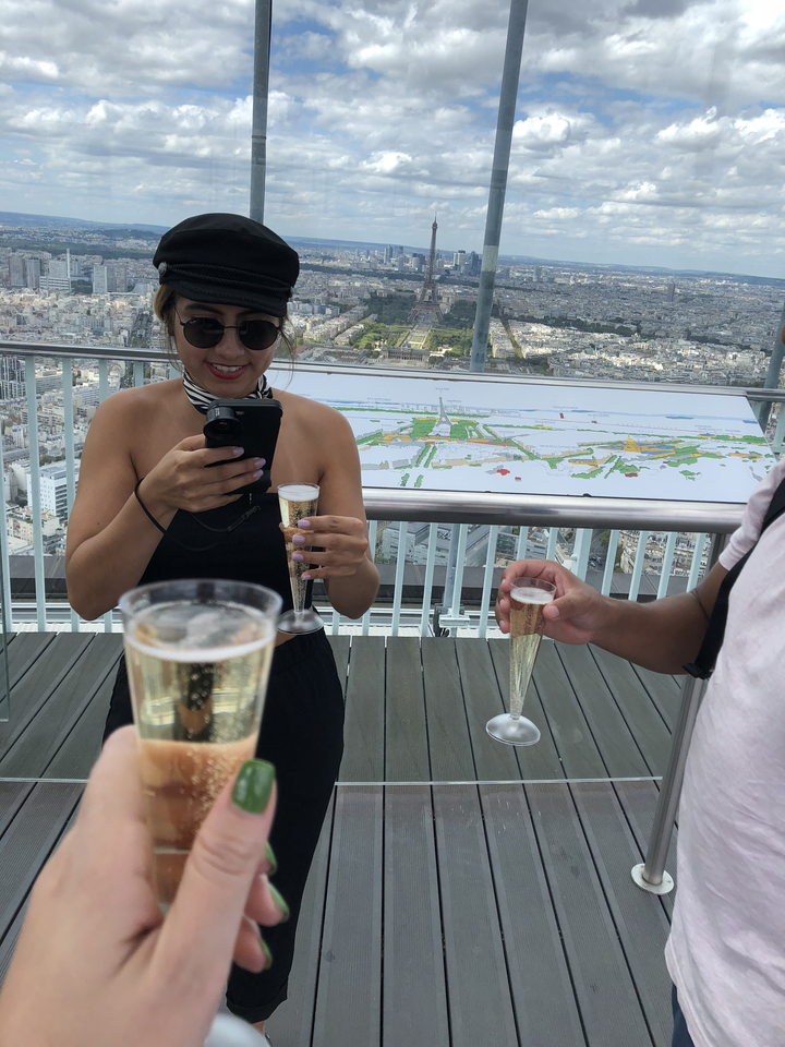 Femme prenant une photo avec son téléphone tout en tenant un verre de champagne.