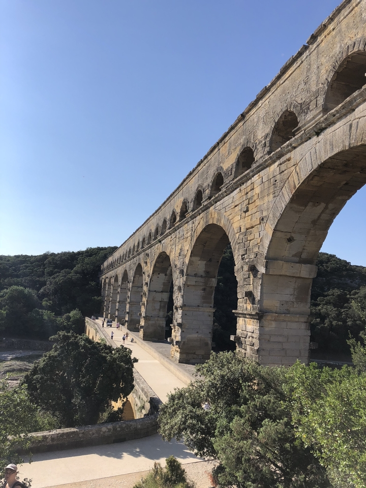 Pont-aqueduc romain antique dans un cadre rural ensoleillé.