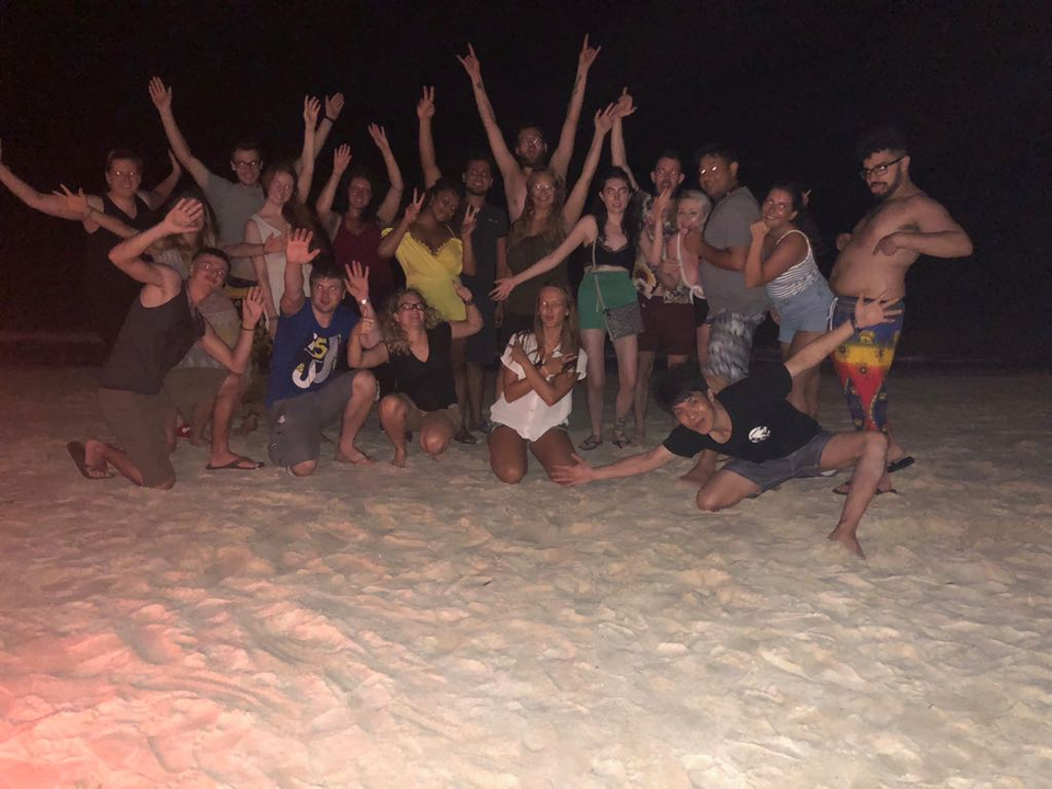 Group of people posing on a beach at night.