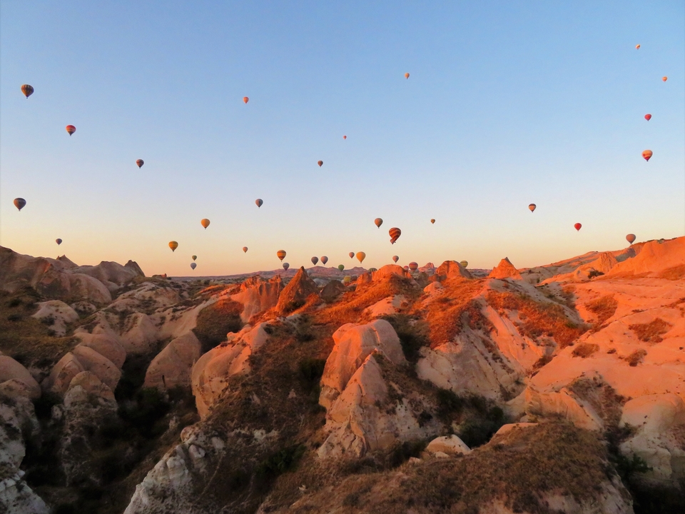 Hot air balloons over a rocky landscape at sunrise.
