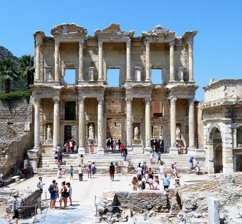 Ancient ruins visited by tourists under a clear sky.