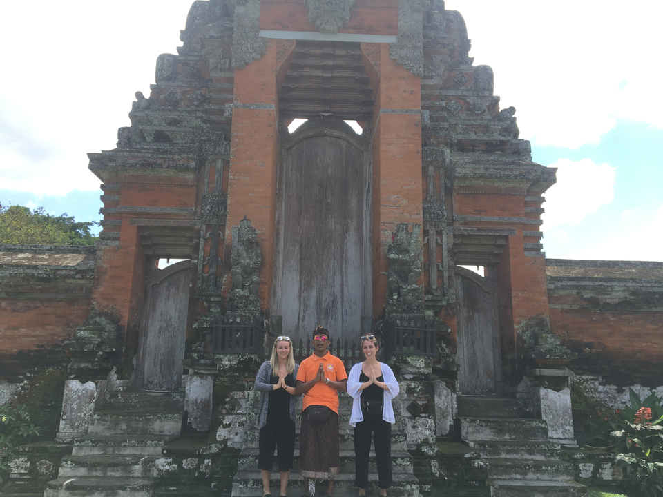 People posing in front of an ornate traditional gate.