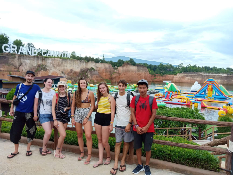 A group of people posing in front of a water park and cliffs.