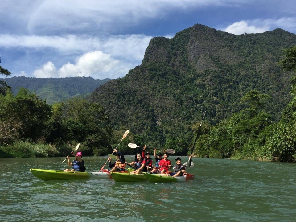 Group kayaking in a scenic river with mountains.