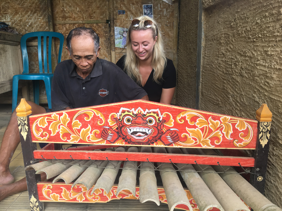 Woman observing a man playing a traditional instrument.