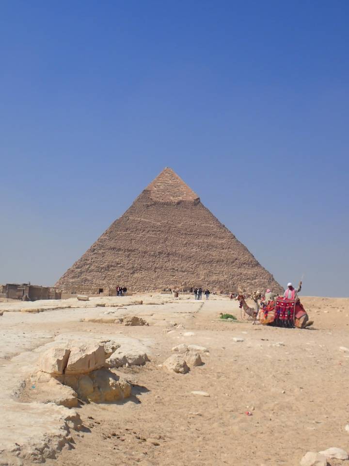 Large pyramid with tourists around on a sunny day.