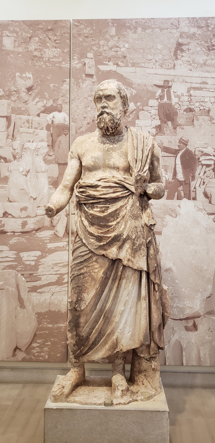 A close-up of an ancient stone statue in an archaeological setting.