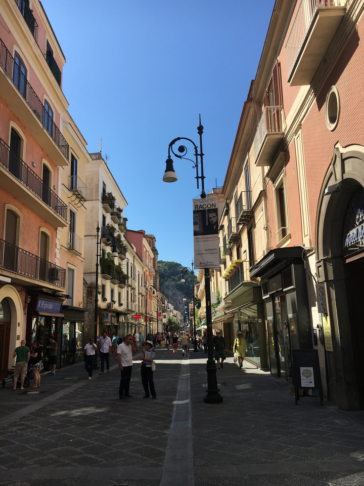 A busy street with historic buildings and people walking.