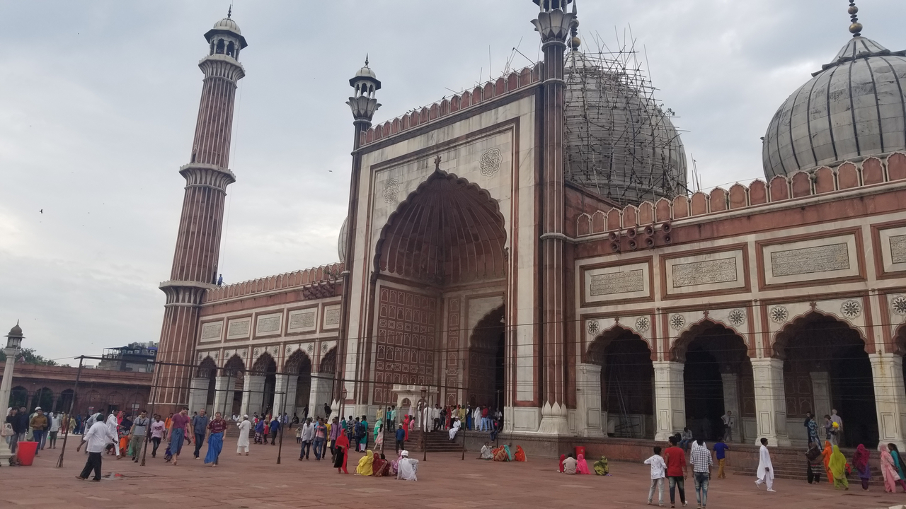 Large mosque with visitors in the courtyard.