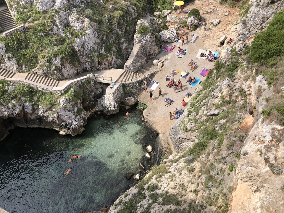 People relaxing and swimming in a rocky cove.