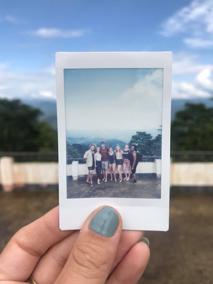 Polaroid photo of a group standing together with a hilly backdrop.