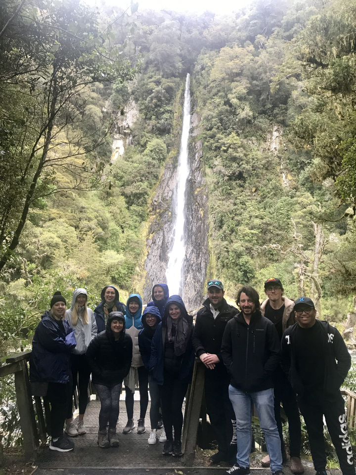 Group of people in front of a waterfall.