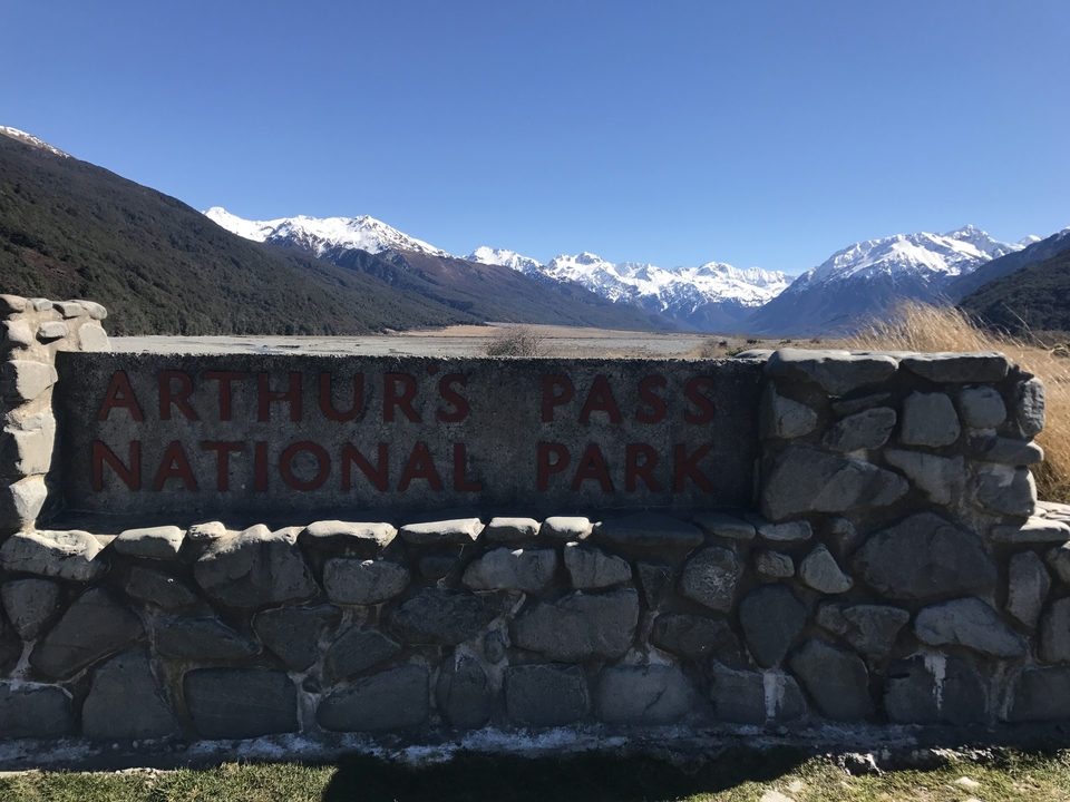 Arthur's Pass National Park sign with mountains in the background.