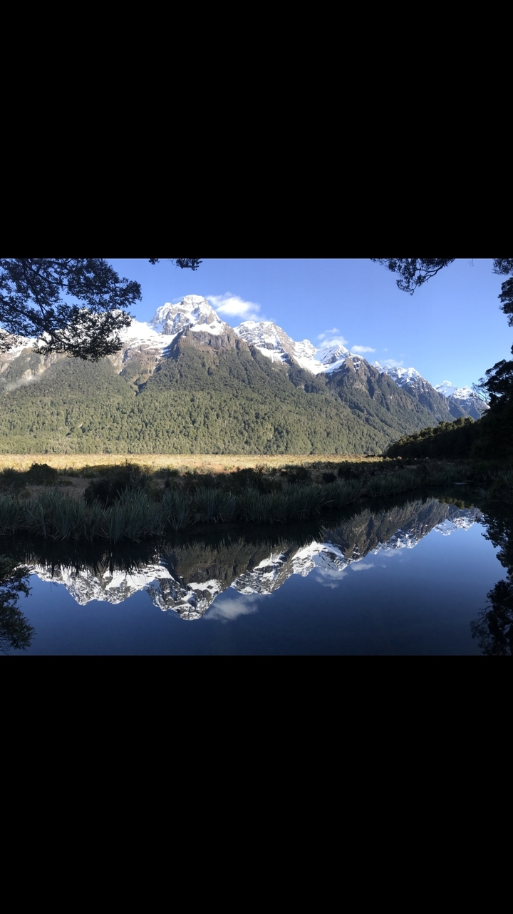 Snow-capped mountains reflected in a calm lake.