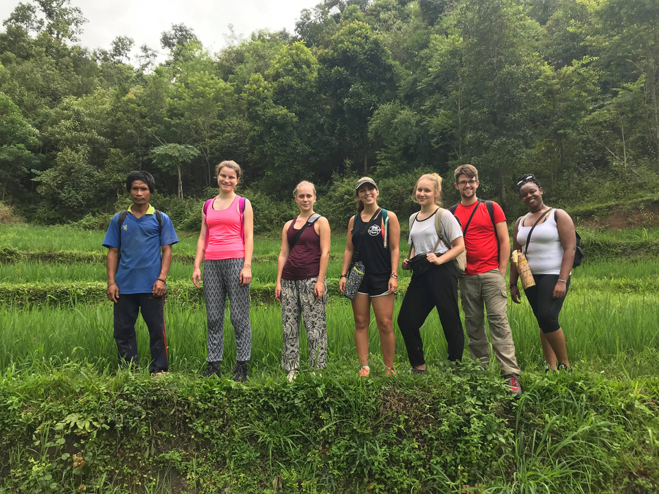 Group of people posing in a lush green field.