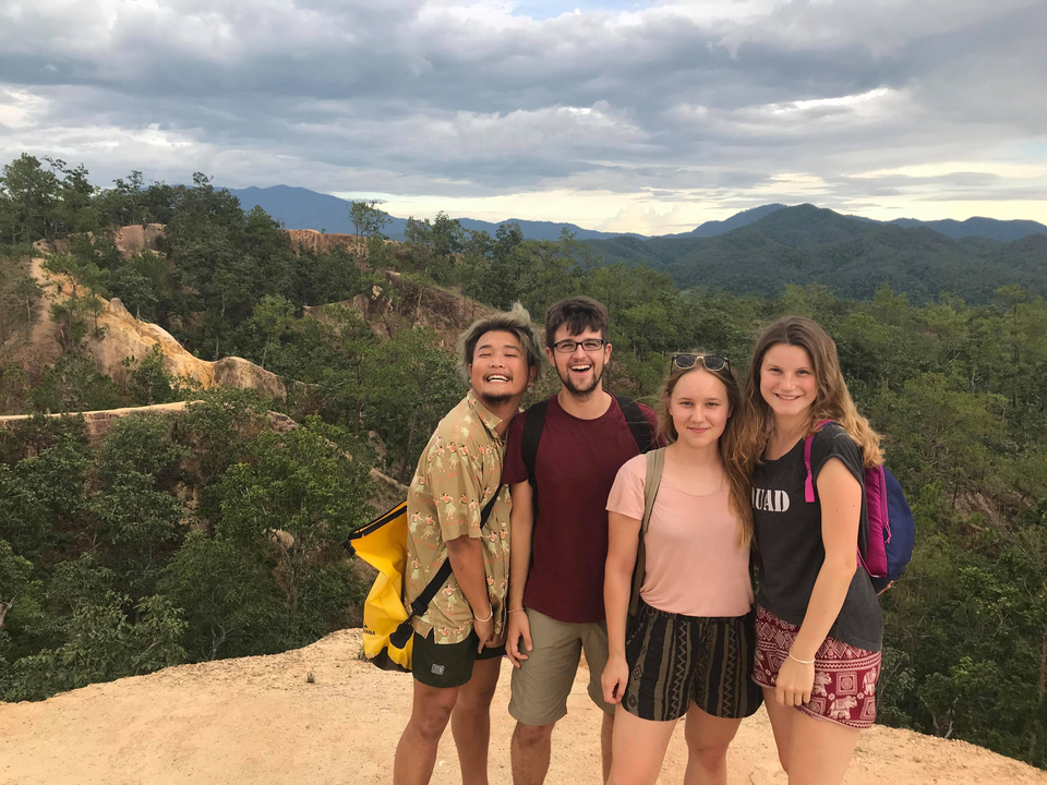 Group of friends smiling outdoors with hills in the background.