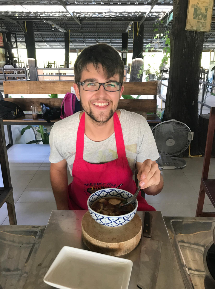 Man wearing an apron and smiling while holding a bowl.