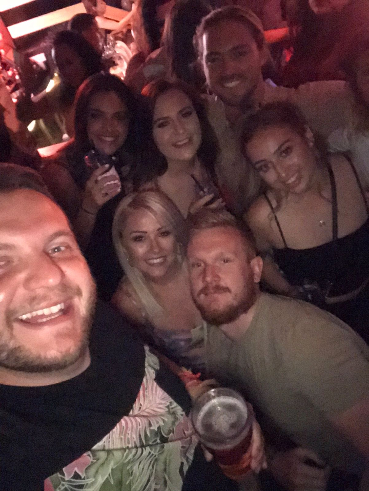Group of people smiling in a dimly lit environment.