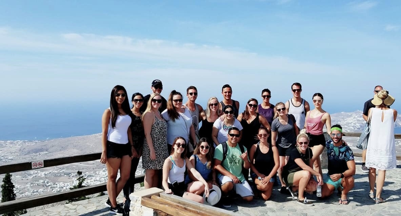 Group photo with ocean in the background and clear sky.