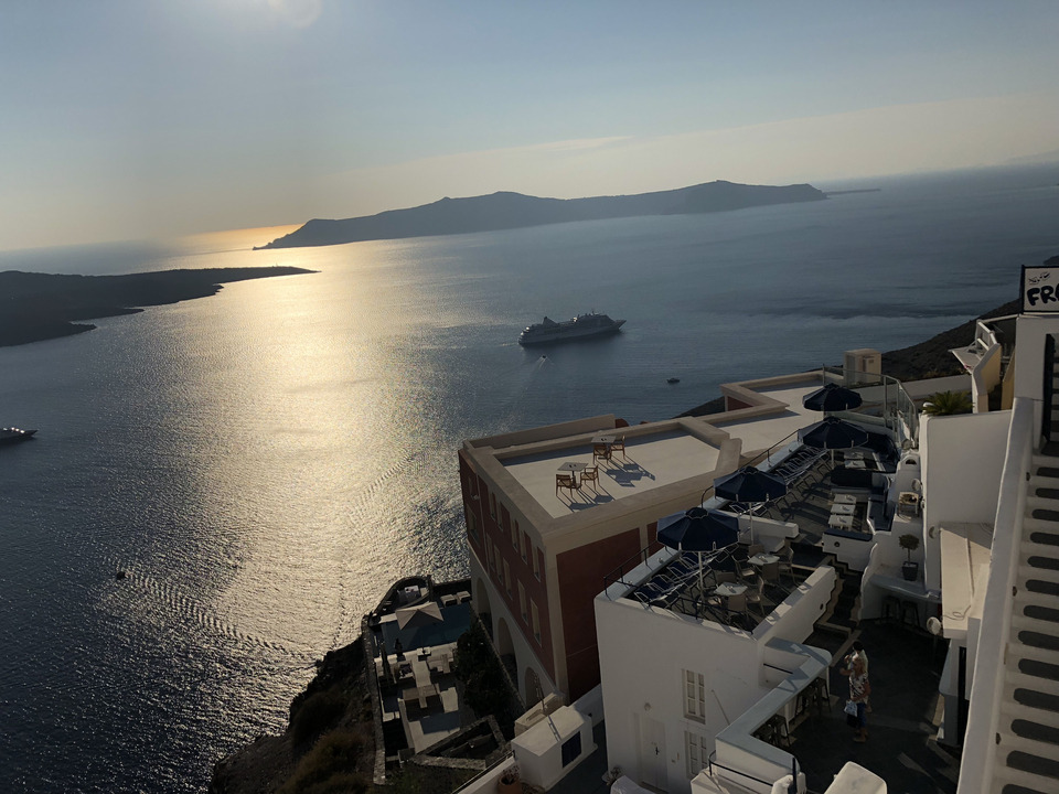 Seaside view with cruise ship and islands during sunset.