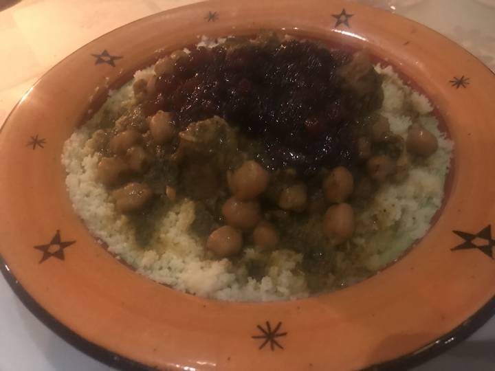 A dish with couscous, chickpeas, and sauce.