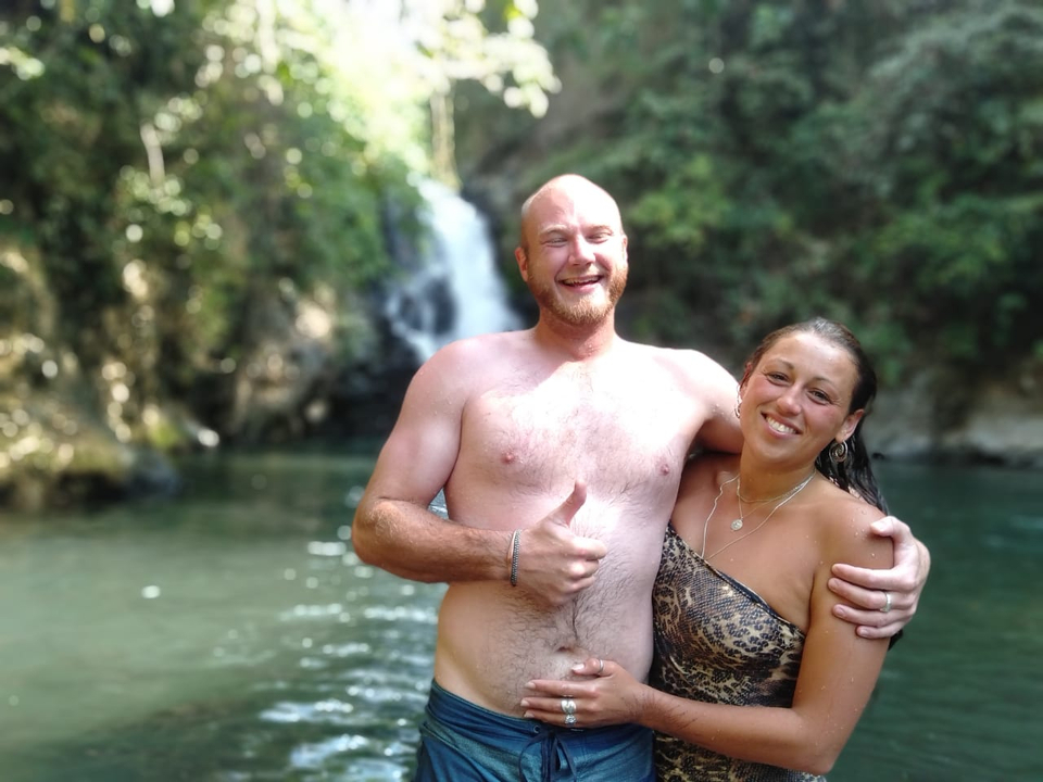 Couple smiling in front of a waterfall.