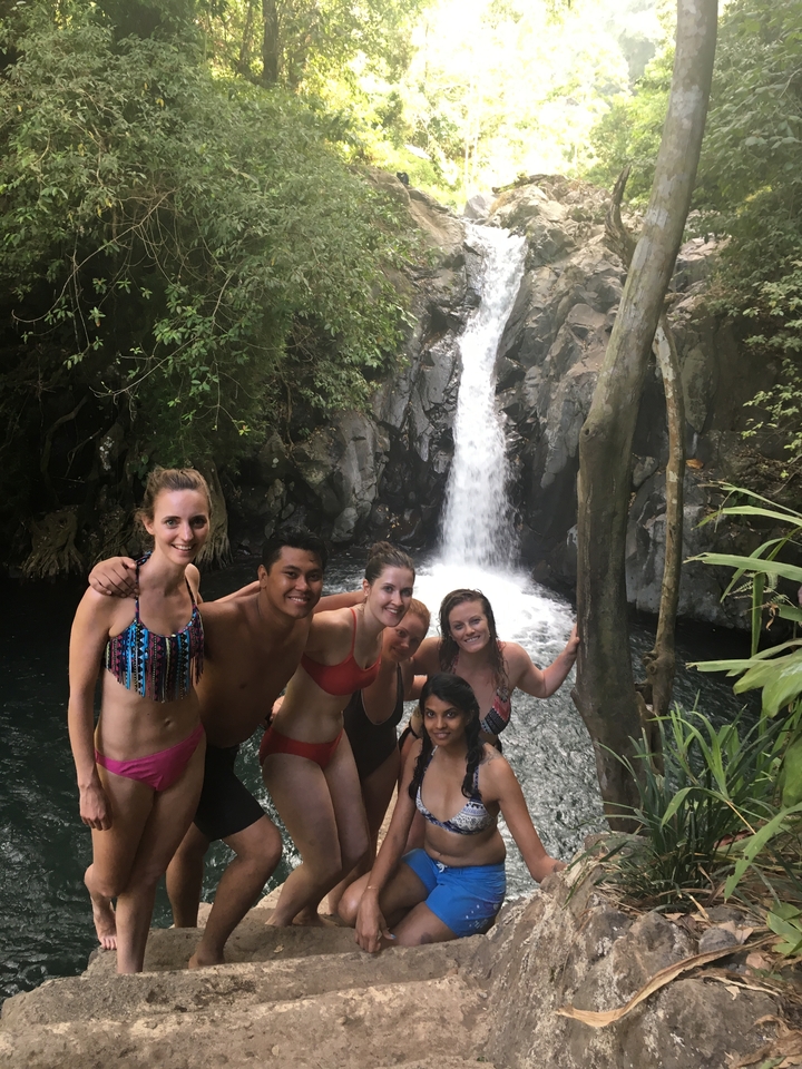 Group of people posing with a waterfall in the background.