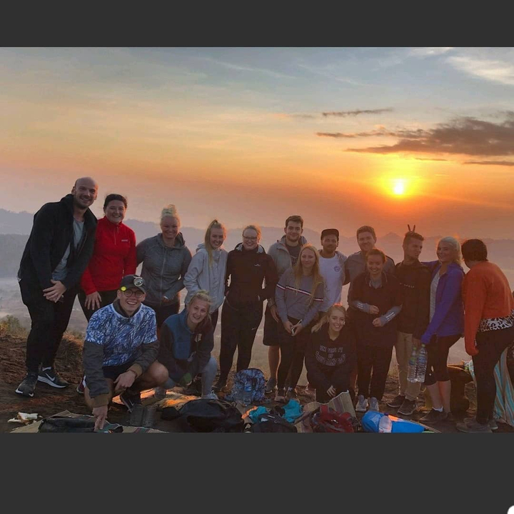 Group of people at sunrise on a mountain.