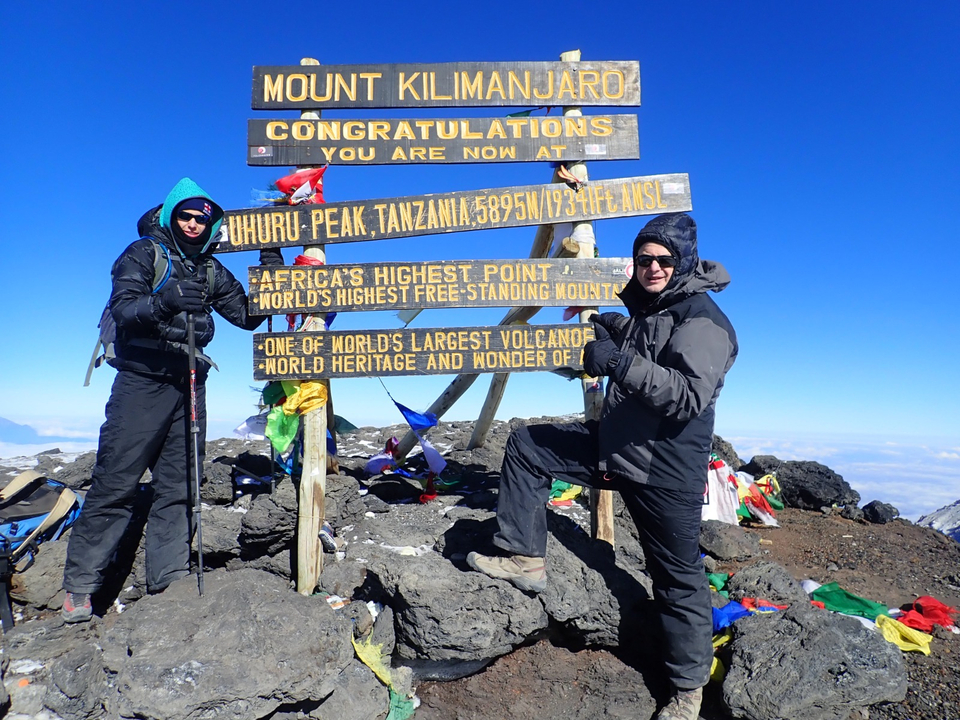 Deux personnes posant au sommet avec des panneaux.