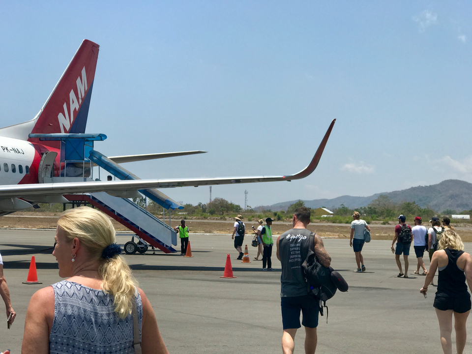 Des personnes embarquant dans un avion avec un paysage montagneux pittoresque en arrière-plan.