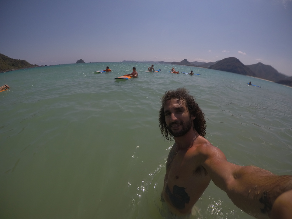 Person taking a selfie in the sea with distant hills.
