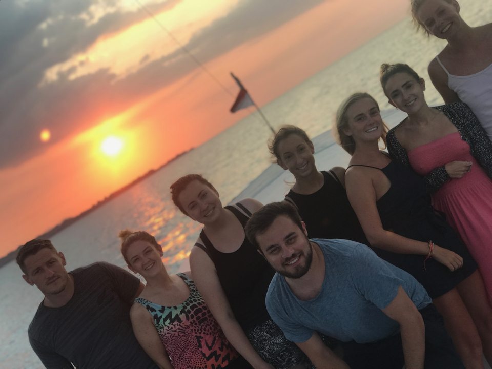 Group of people posing on a boat during sunset.