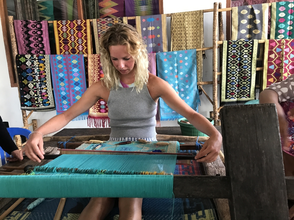 Woman working on traditional weaving with colorful threads.