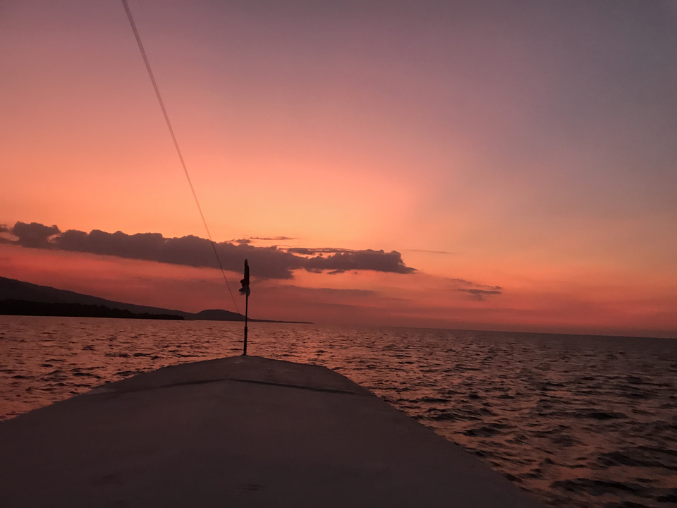 Sunset over the ocean with a boat's outline visible.