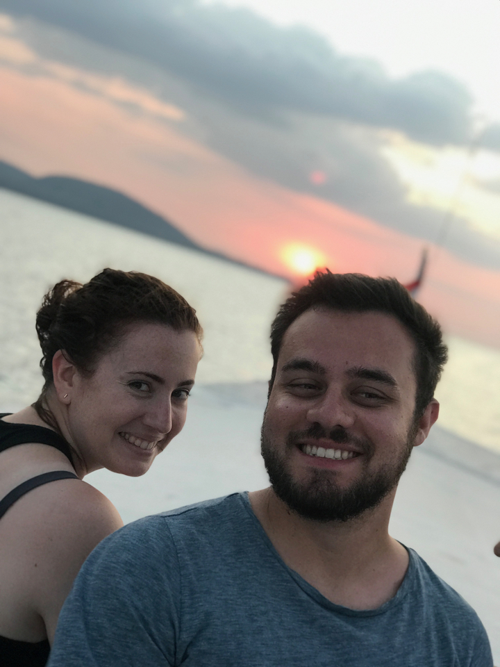 Close-up of two people smiling at sunset on a boat.